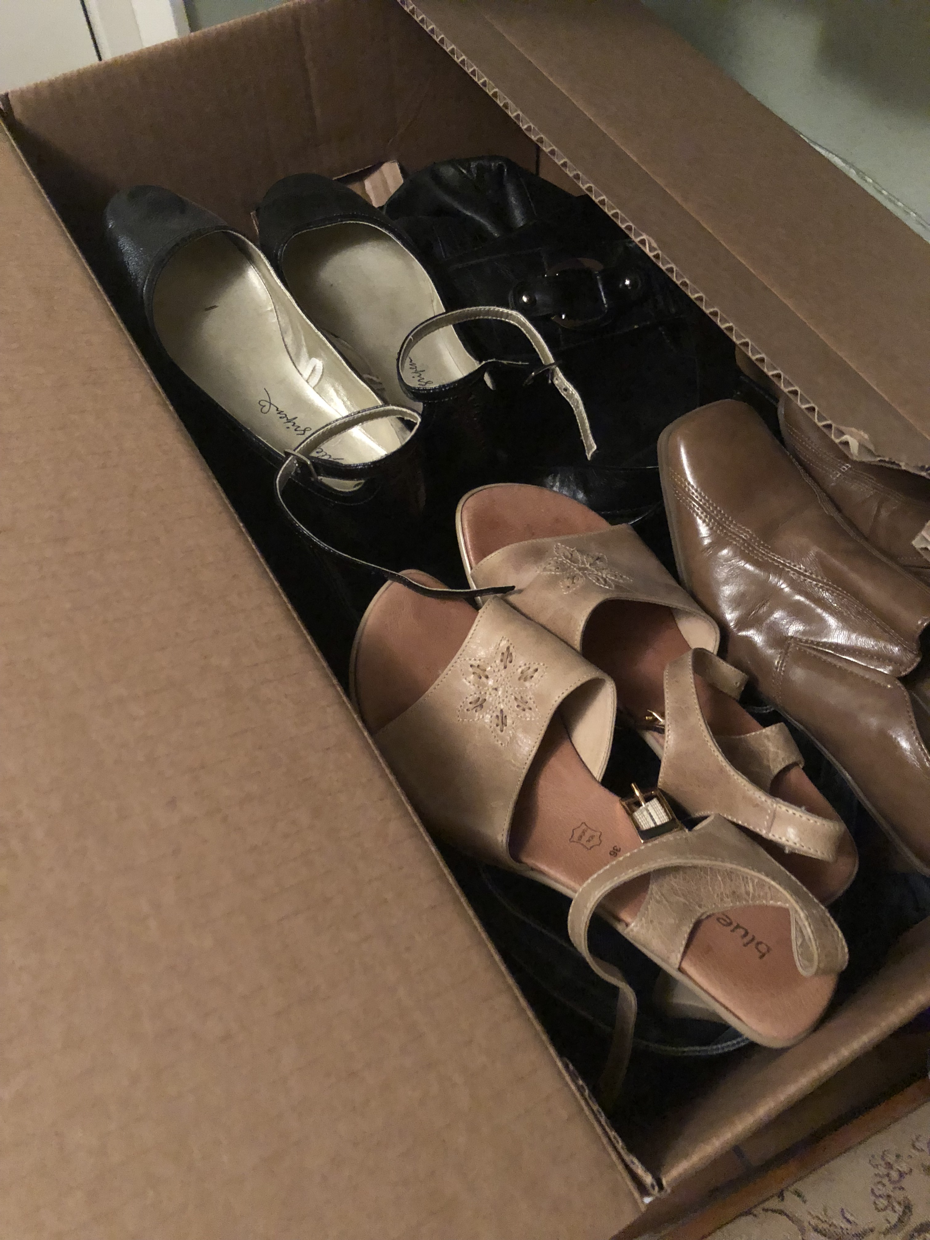 A storage-box with a lot of stuff. On top is a couple of nice shoes. 